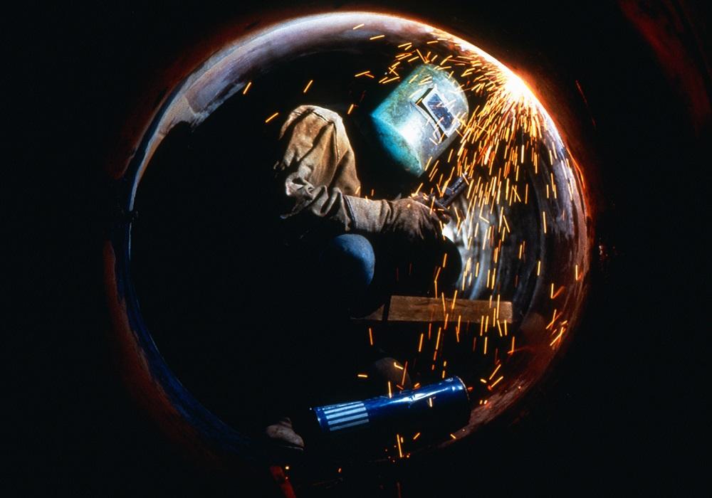 Welder working inside of a large pipe