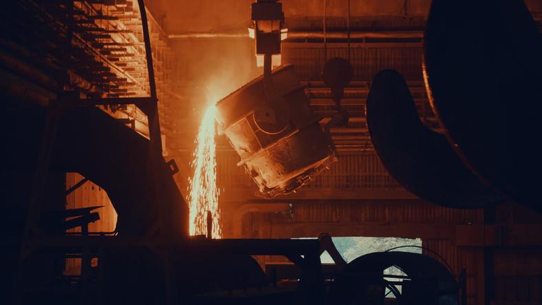 Molten metal is poured from a large vat in a steel-making facility.