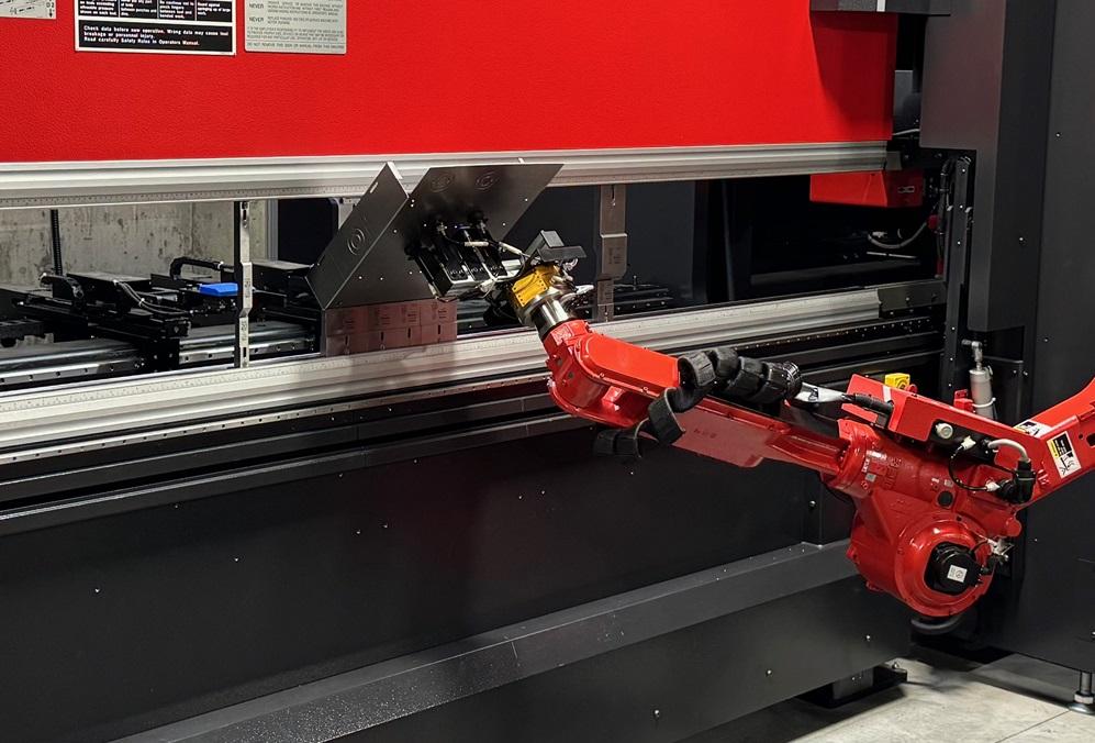 A robot feeds a metal part to a press brake.