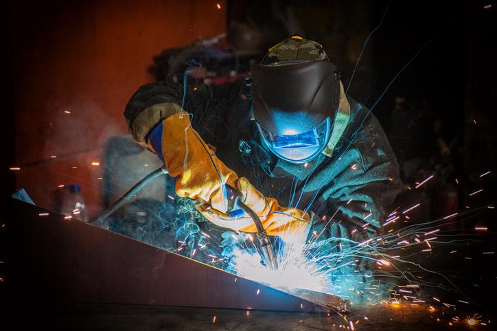 A worker welds a piece of metal in a factory.