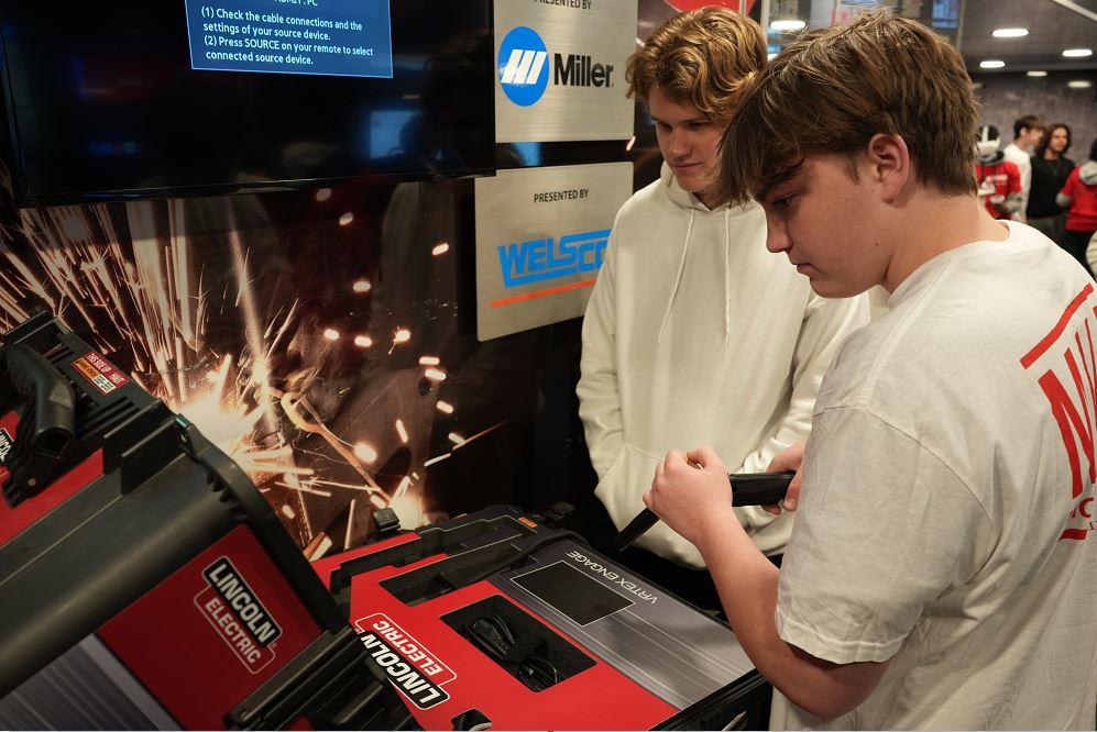 Two students use a virtual reality welding machine.