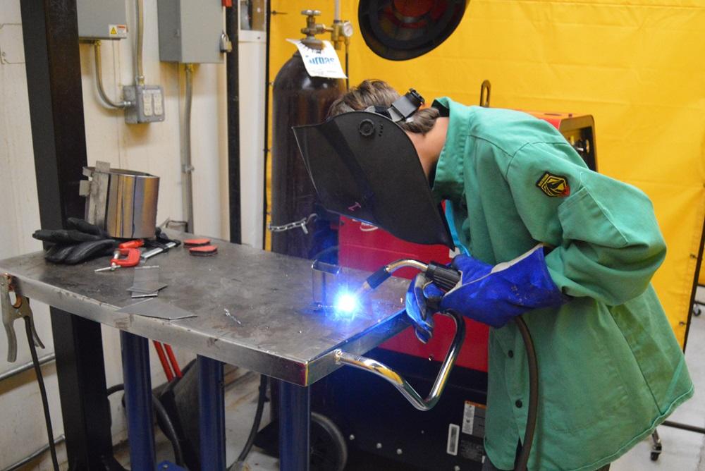 A camp attendee welds.