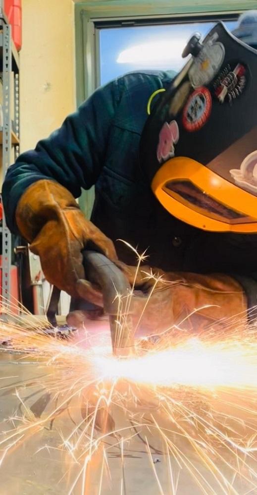 A person welds sheet metal.