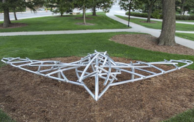 A sculpture made of aluminum rods sits in a park.