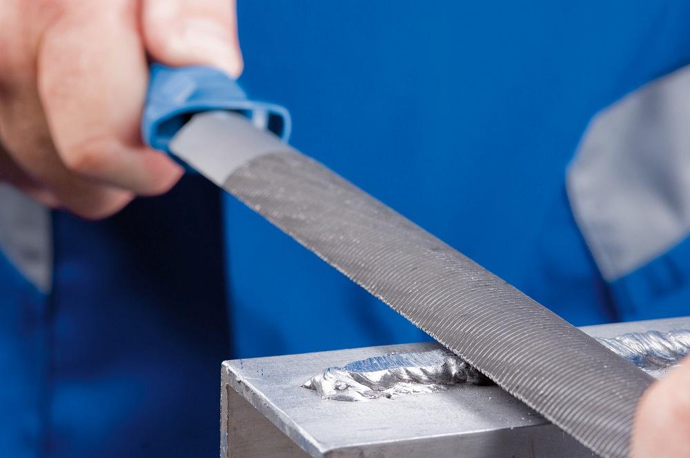 A file is used to grind down a weld bead on aluminum.