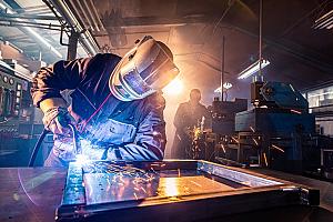 part presentation manufacturing Two people weld in a shop.