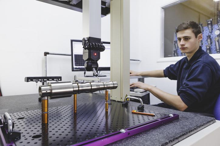 A young person operates a coordinate measuring machine.