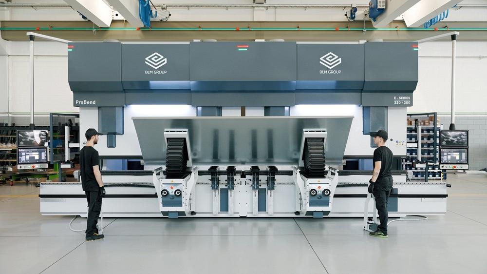 两名操作员站在大型串联式折弯机前。