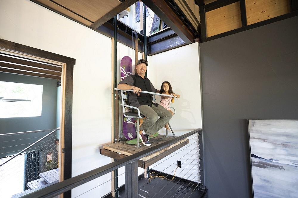 A man and girl sit on an interior ski-lift elevator