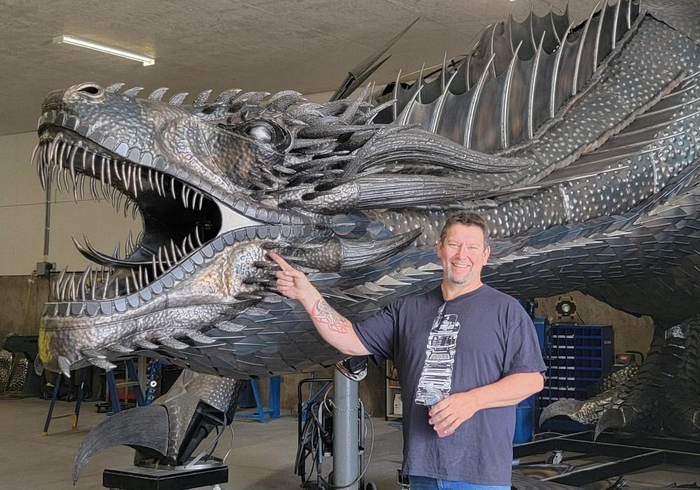 Metal art sculptor and artist with a metal sculpture of a dragon