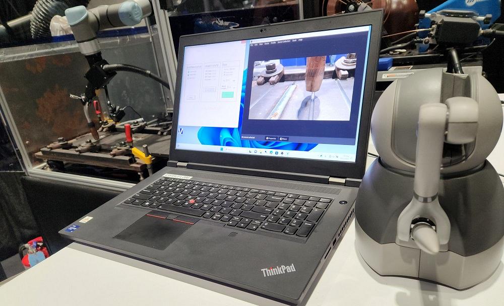 A laptop computer sits between a robot and joystick.