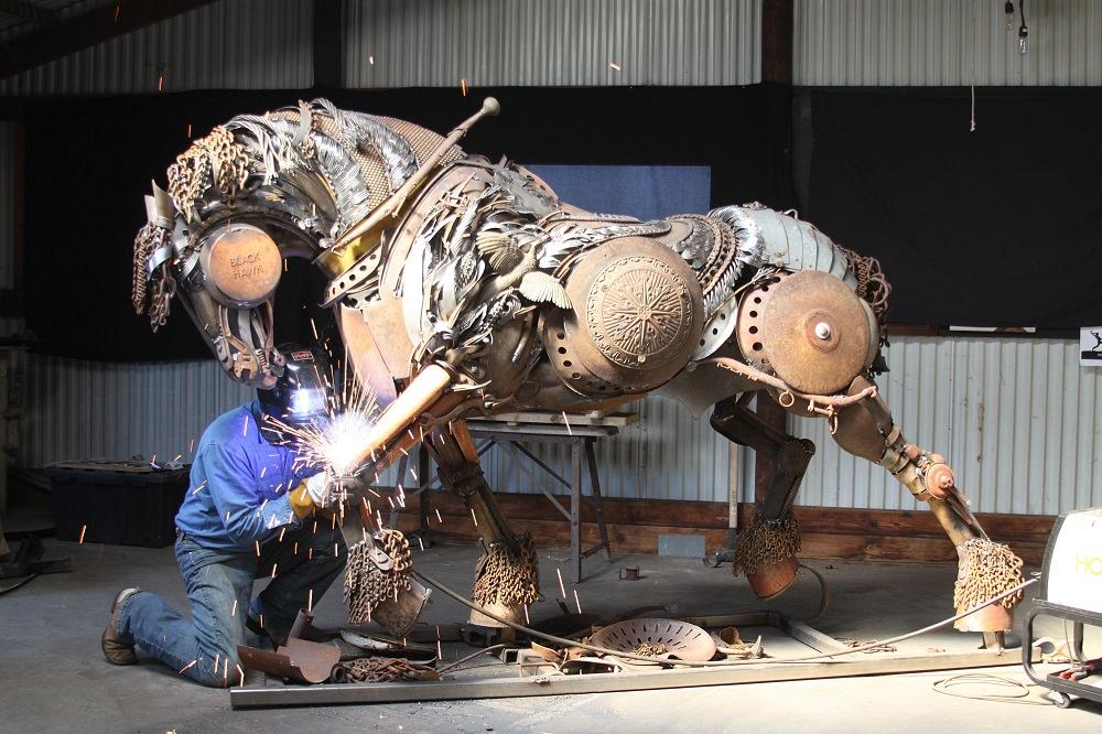 John Lopez welds a piece onto the sculpture of a horse.