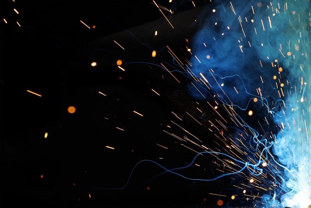 Close up view and background of the gas metal arc welding (GMAW) process with sparks, light, bokeh effect and smoke.