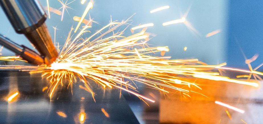 A laser welds a square metal tube as sparks fly.