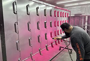 A person powder coats small metal parts.