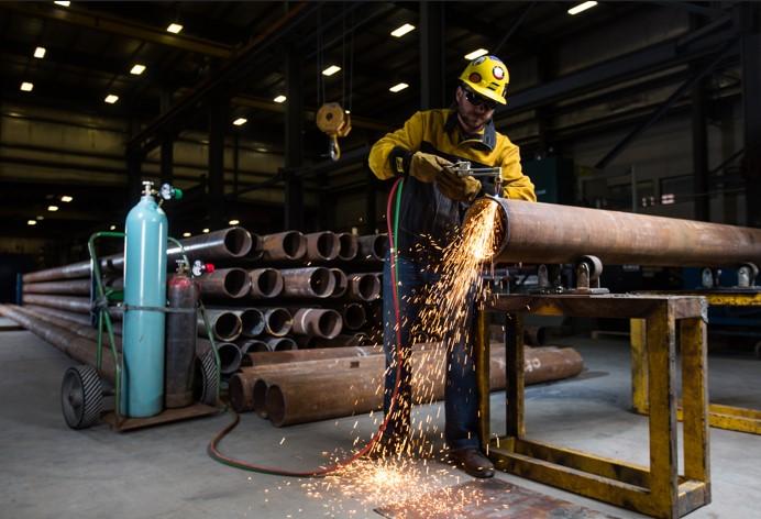 A fabricator cuts a pipe with an oxyfuel torch.