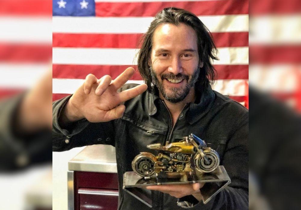 Keanu Reeves with a metal sculpture of a motorcycle