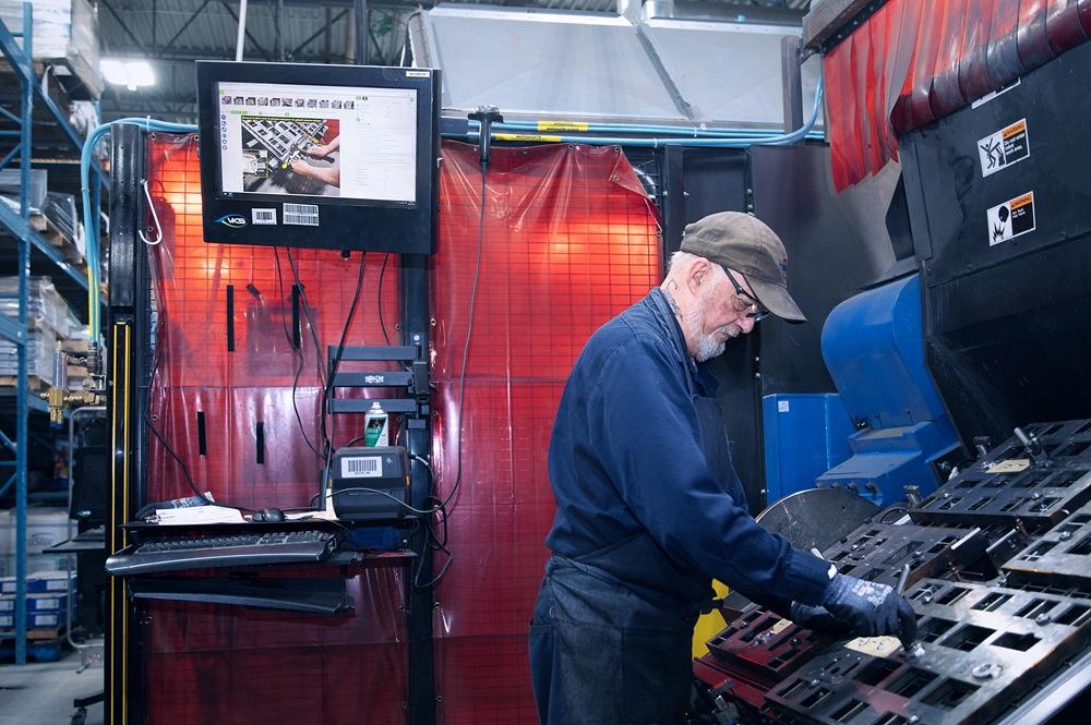 A technician adjusts fixturing in a robotic welding cell.