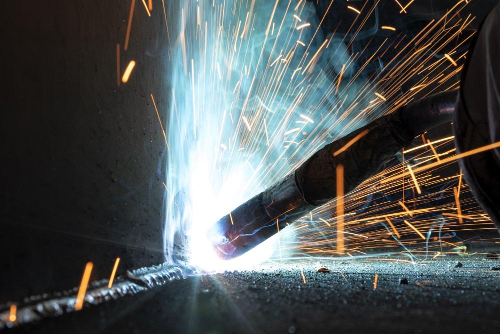 Close up view gas metal arc welding (GMAW) process with sparks, light and smoke. It is a high-speed, economical process that is sometimes referred to as metal inert gas (MIG) welding.