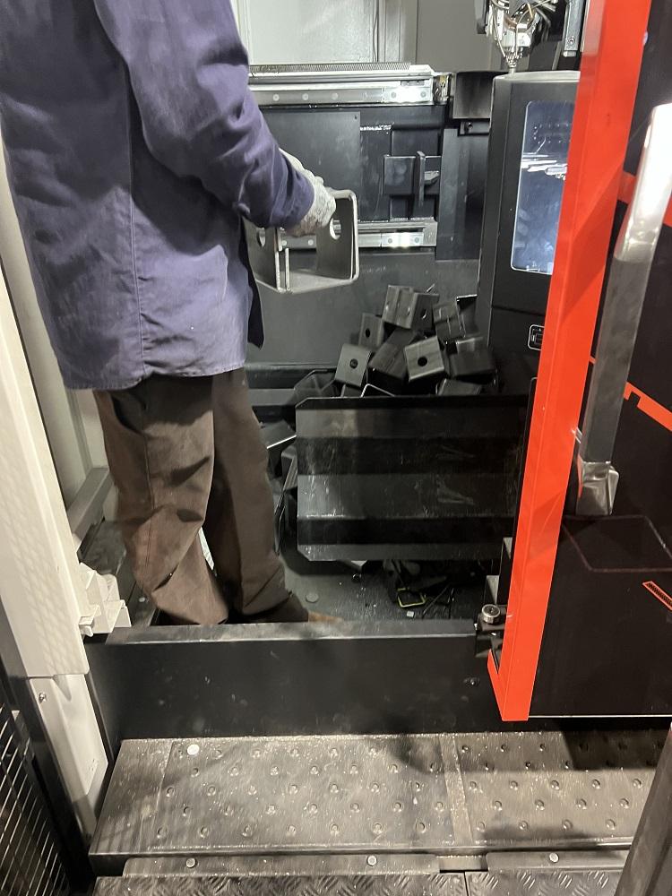A person unloads square cut tube from a machine.