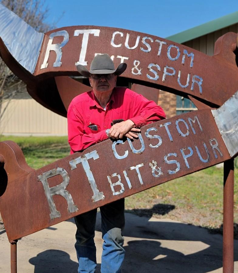 Rod Teuscher leans against his company’s sign.