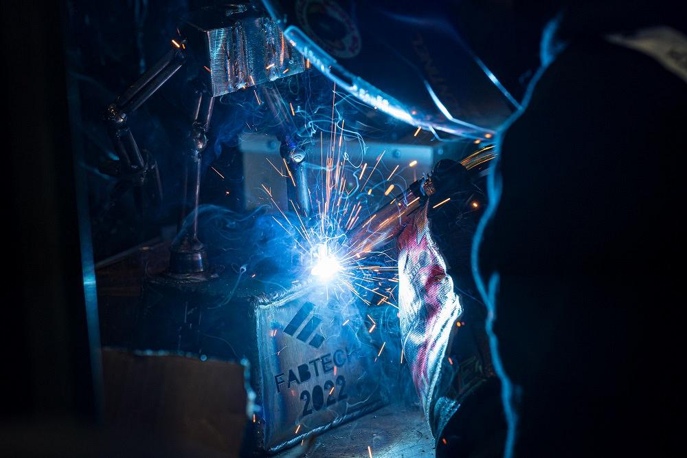 A welder arc welds a piece of metal.