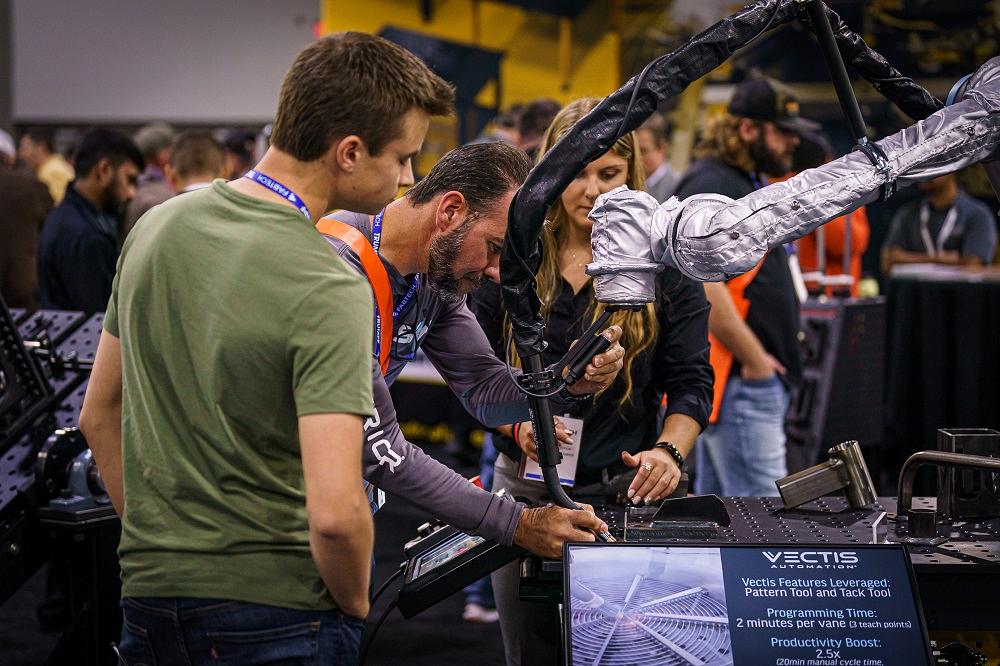 People view a robot arm in action.