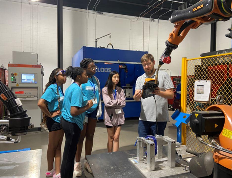 Campers learn how a robot welder works.