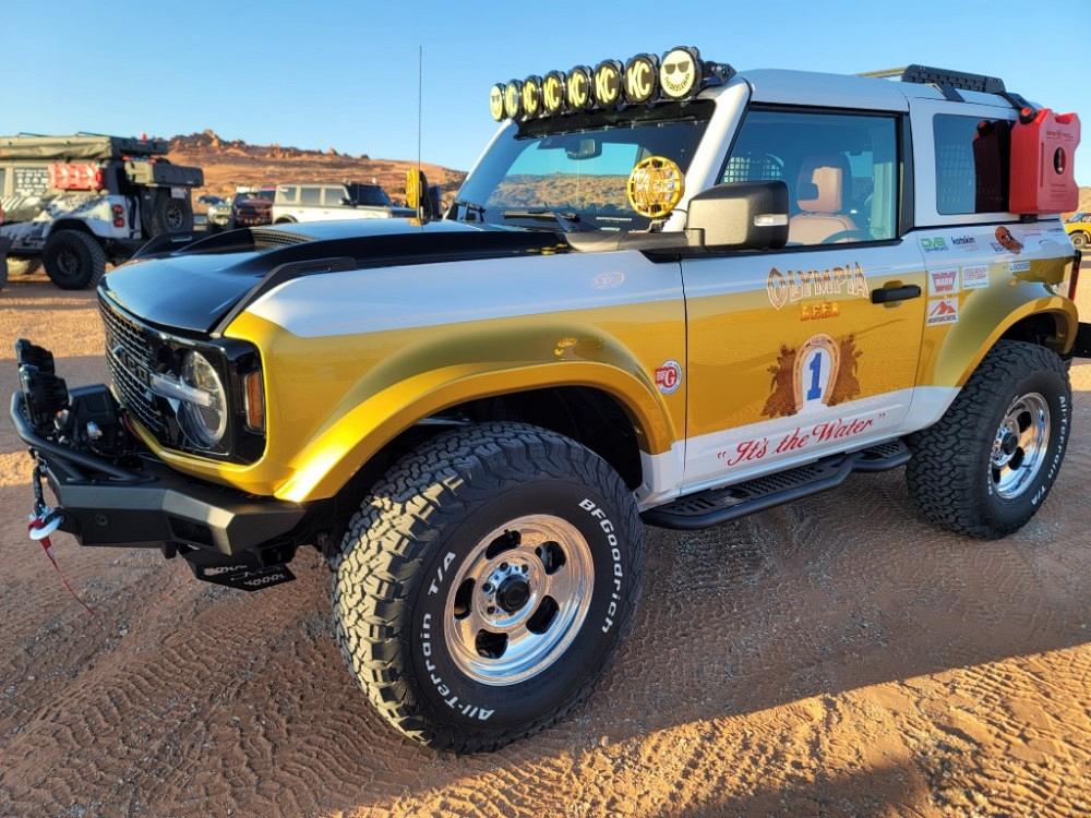 A Ford Bronco with an Olympia Beer paint job is shown.