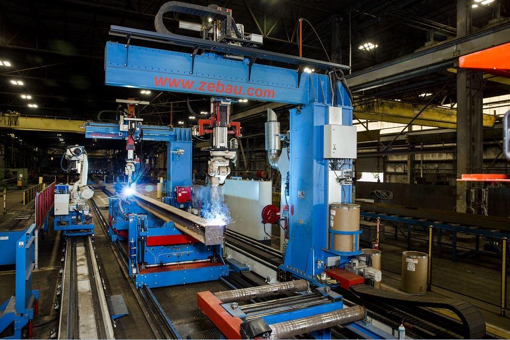 part-handling and -fitting robot places piece for welding robot