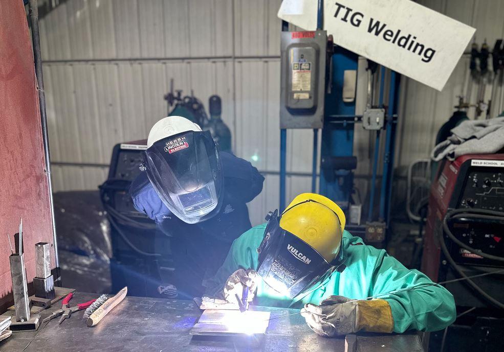 A young welder is trained to do gas tungsten arc welding.