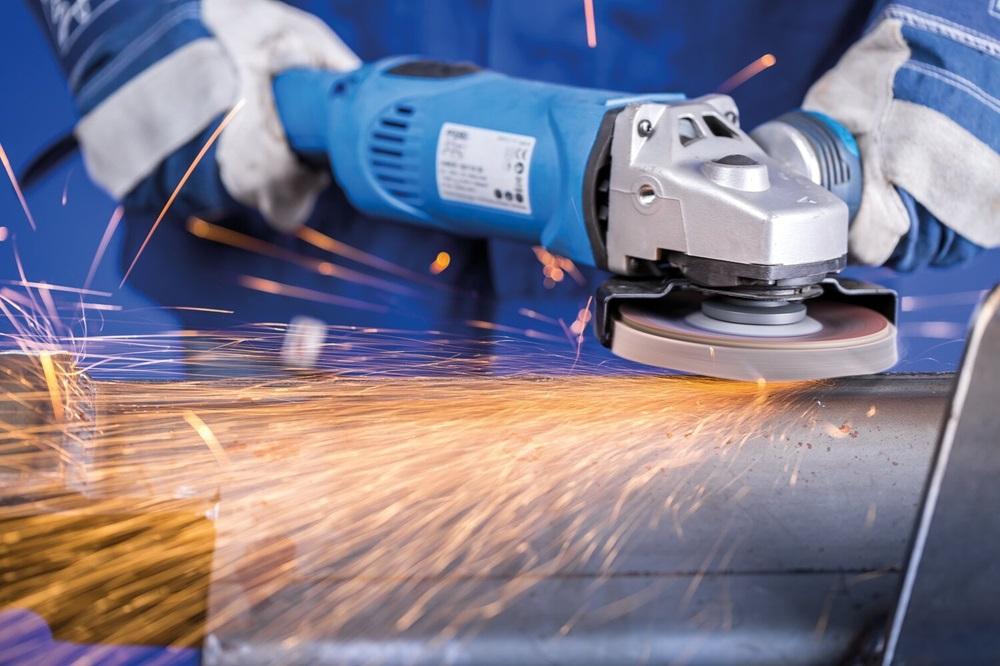 A person uses a grinder to finish a piece of metal, and sparks fly.