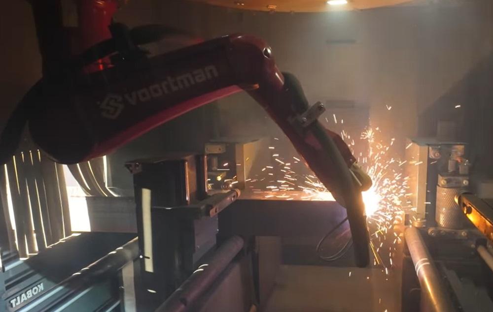 A robot plasma cuts a piece of metal.