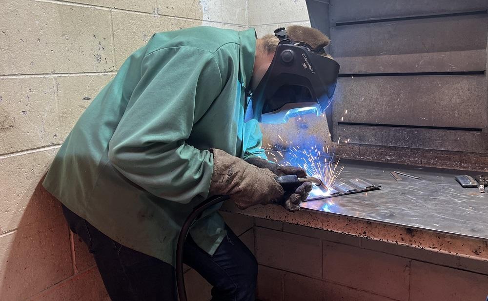 A student welds a piece of metal.