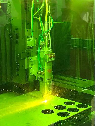 The fiber laser processing head cuts through a sheet of 0.25 steel.