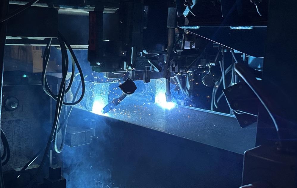  A boom welder works on a piece.