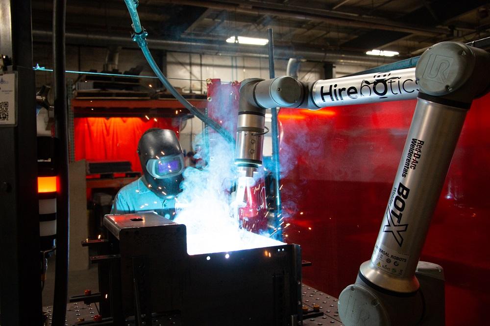 Welder operates a welding cobot in a metal fabrication shop