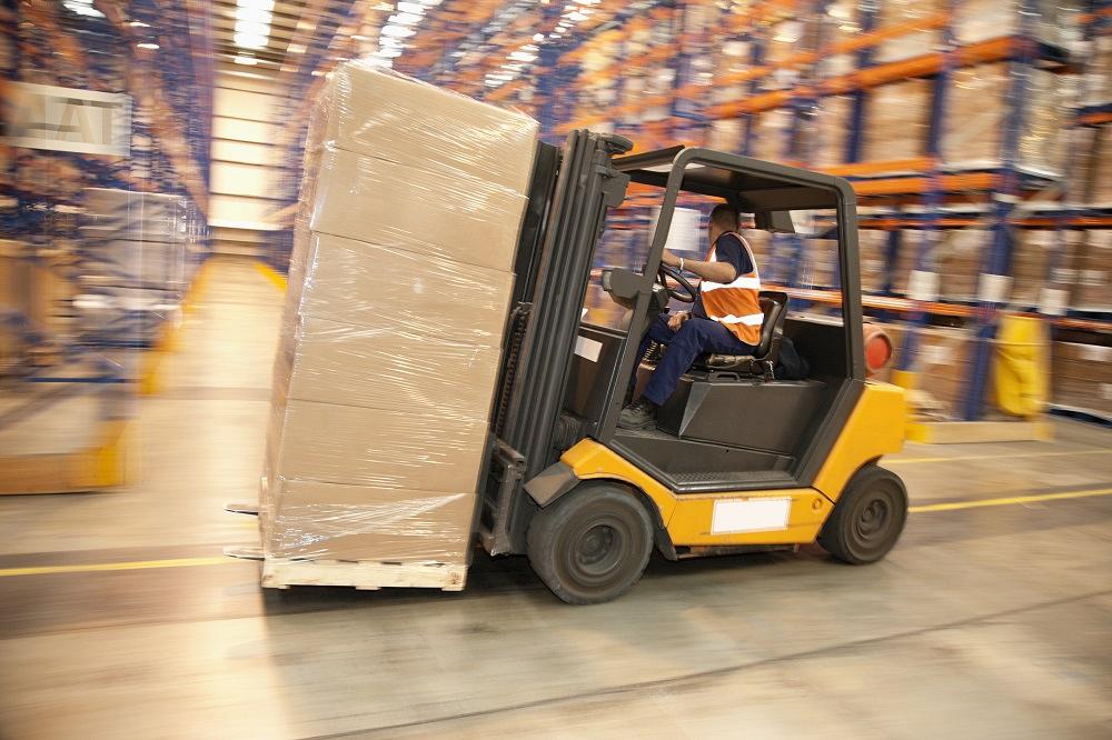 A forklift moves backwards in a warehouse.