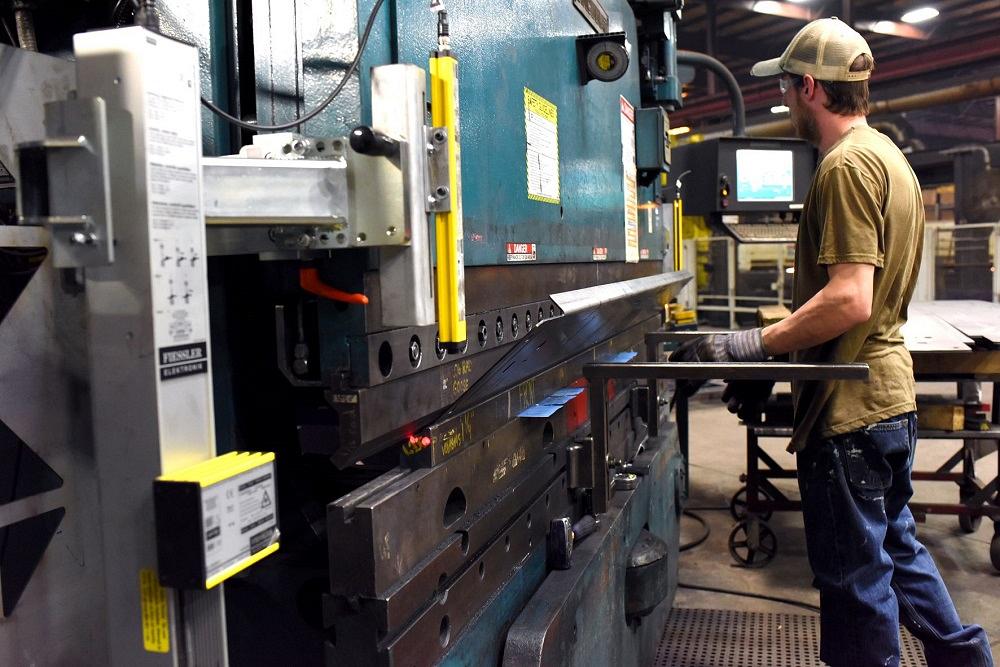 An operator lets go of a metal workpiece as it is bent in a press brake.