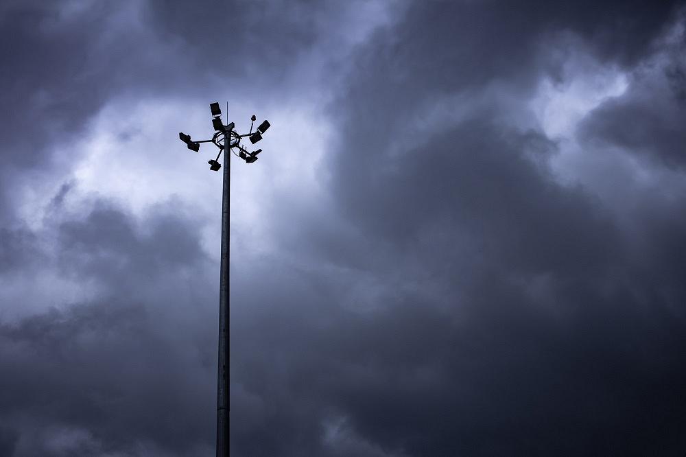 A light pole stands against a stormy sky.