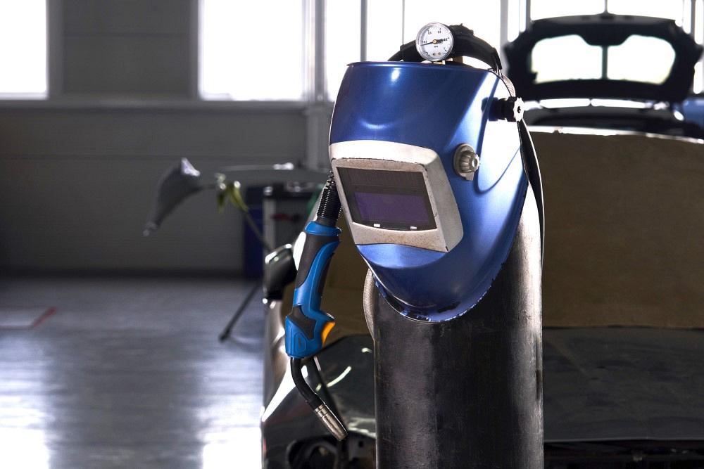 Welding equipment in a car repair station, helmet hanging on a gas tank