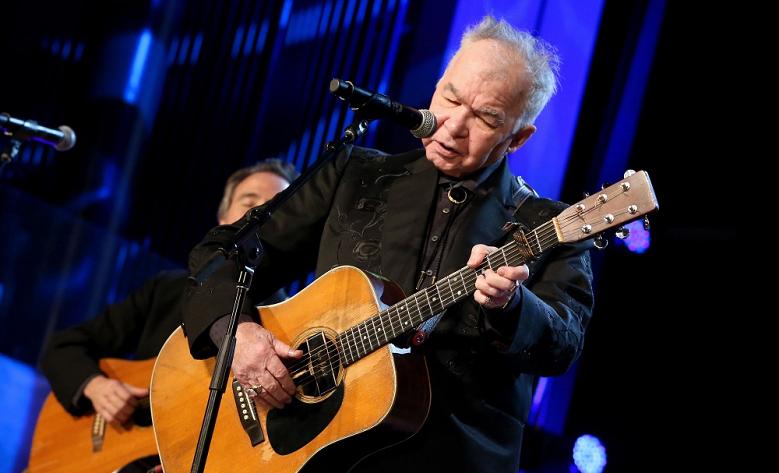 Alt country musician John Prine singing and playing the guitar