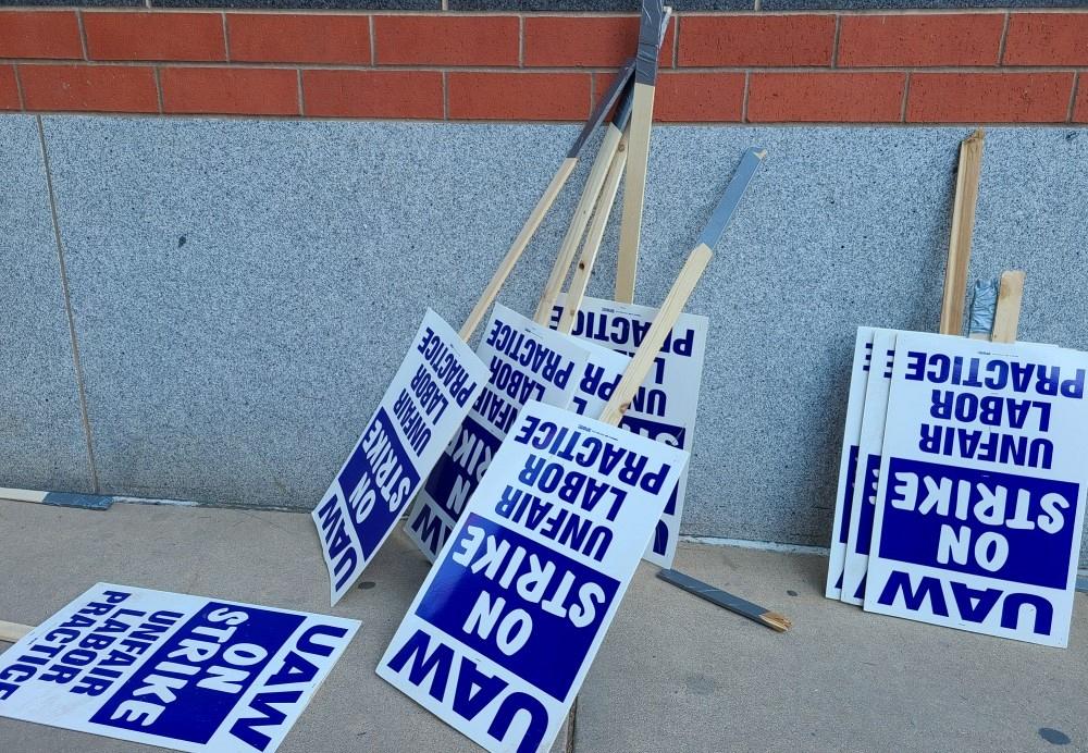 UAW union on strike picketing signs resting on a wall. 