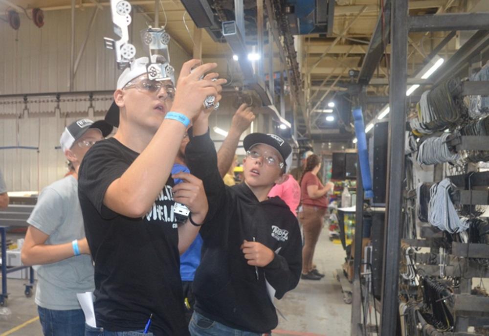 Students hang small metal replica Jeeps on hooks.