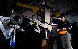 A person oversees a welding cobot in action.