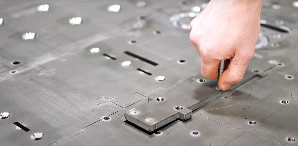 Fabrication shop worker removing laser-cut plate pieces