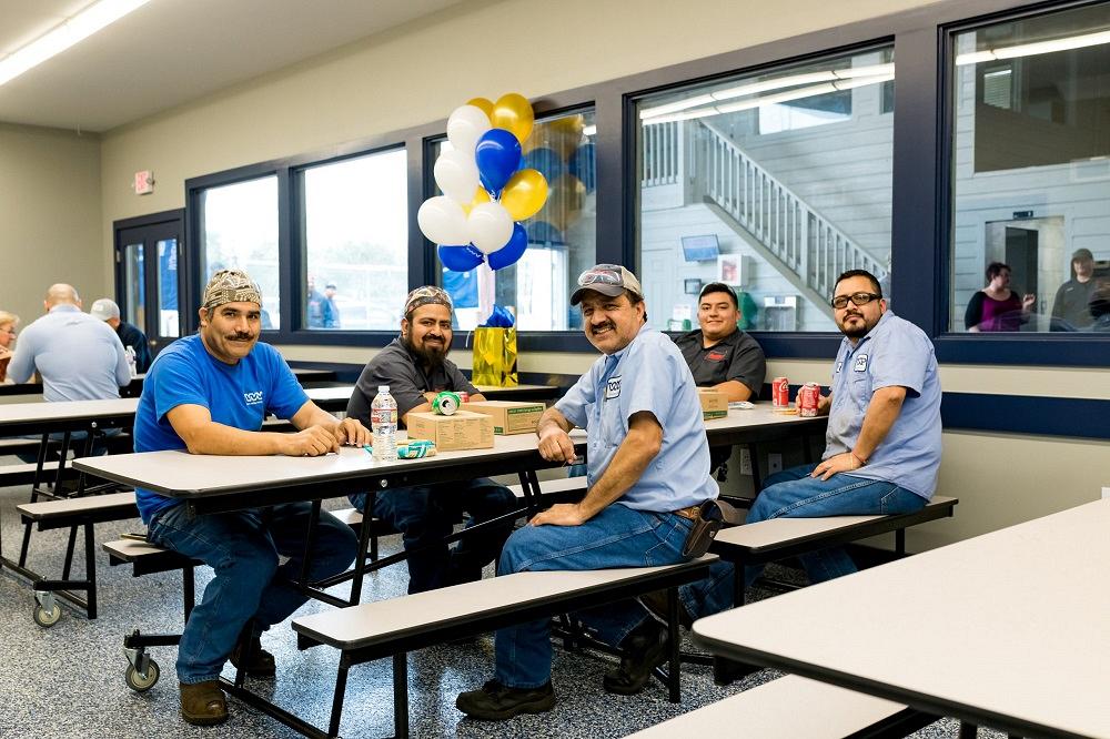 Workers gather at a table in the break room.
