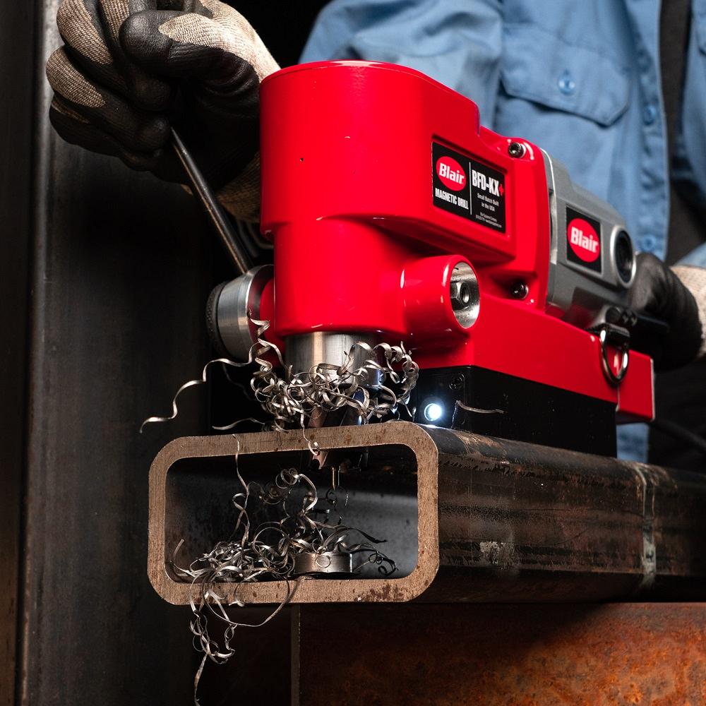 A drill cuts through a thick metal section.