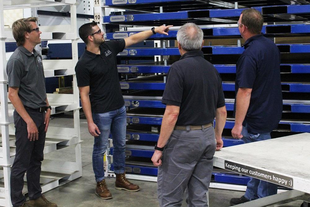 Four men look at a metal storage system.