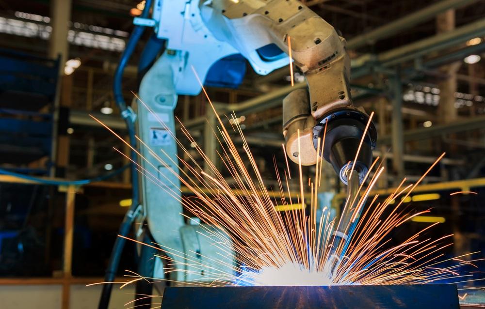 Robot is welding metal part in car factory